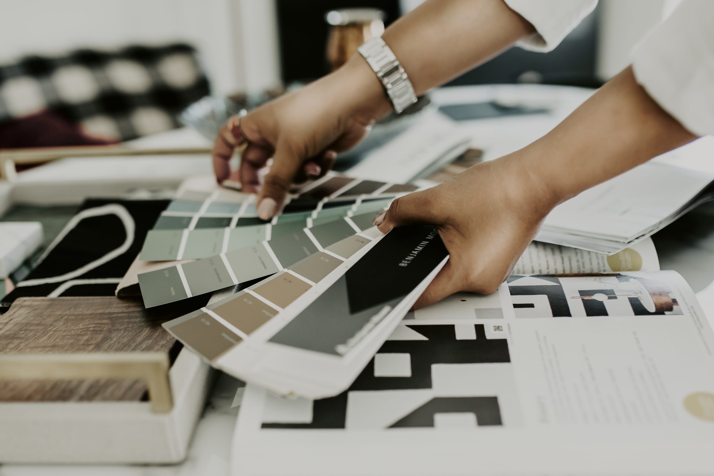 Hands fanning through paint and finish samples on a design table